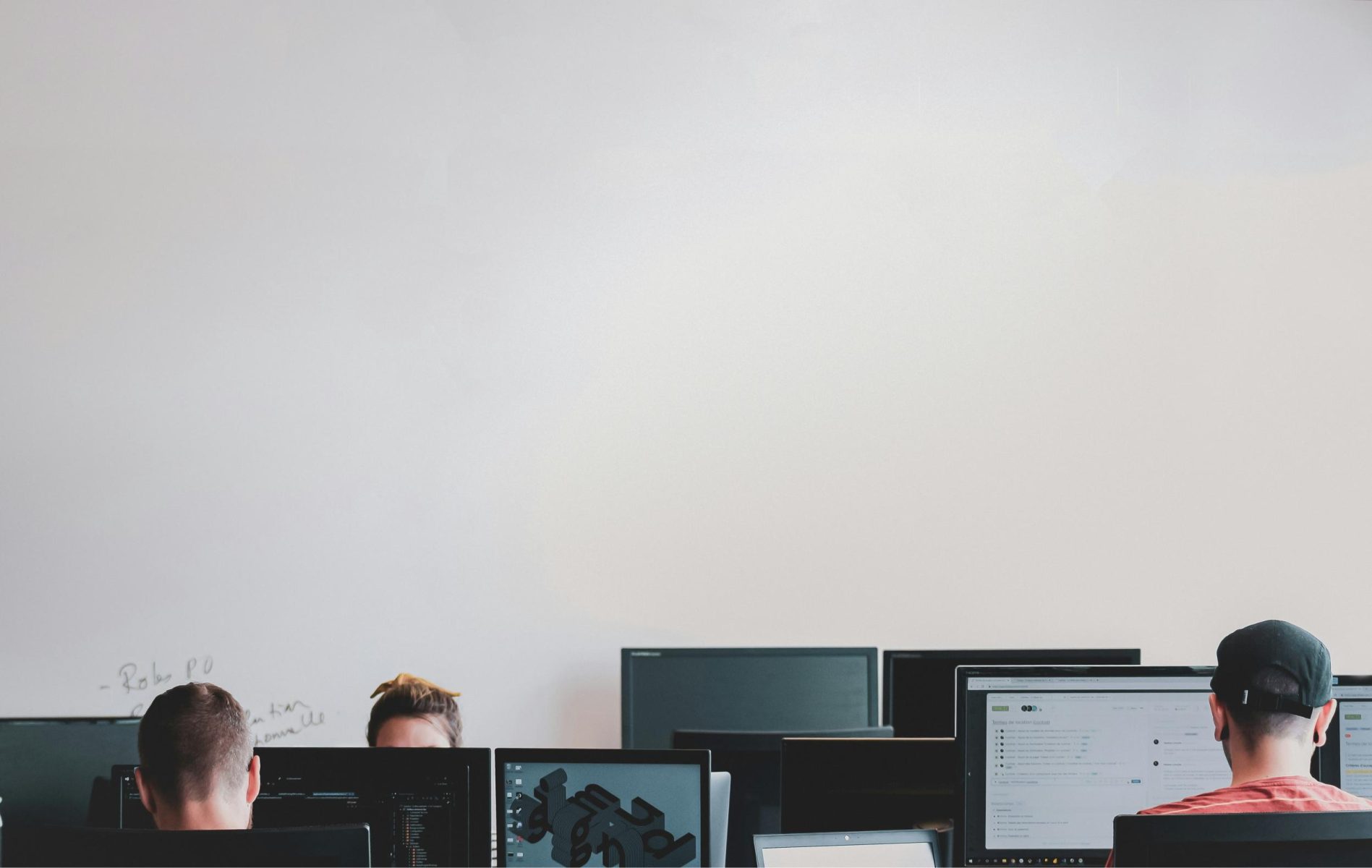 Office setting with multiple people working at computer screens.